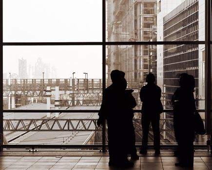 Businessman silhouette standing and talking in front of windows.