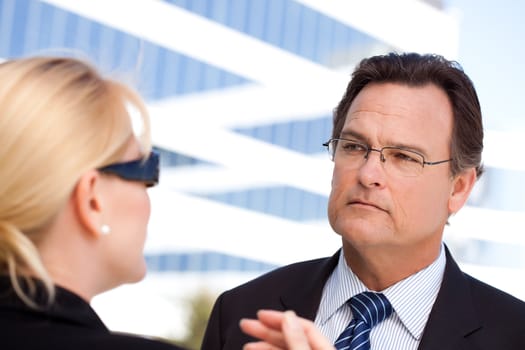 Attentive Handsome Businessman in Suit and Tie Listens to Female Colleague Outdoors.