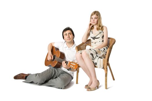 A blond girl and a man playing guitar for her