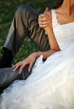 The groom and the bride sit on a grass