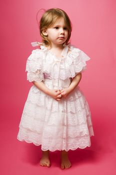 little girl in a white dress on a pink background