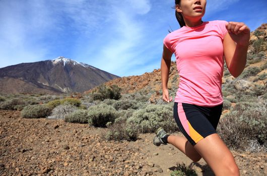 Running. Woman Cross country trail runner running on the mountain / volcano Teide on Tenerife. Beautiful mixed chinese asian / caucasian female model.