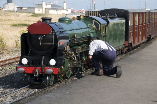 A miniature steam train with the engineer working on the engine