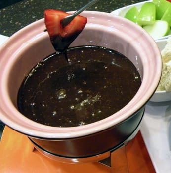 strawberry afterhaving been dipped in melted dark chocolate in a fondue pot.