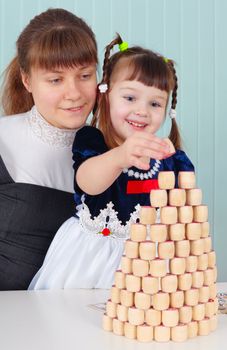 Mom and daughter play - to build a tower at table