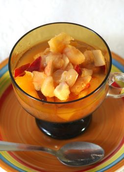 close up of a bowl containing fresh fruit salad and a spoon