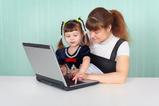Mom shows daughter work on computer at table