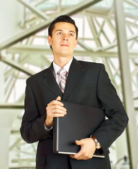 Businessman walking in a corridor of a modern building with laptop