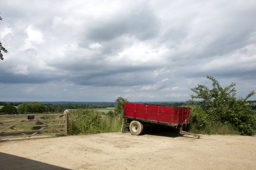 A red farm trailer in a farm yard