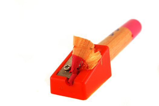 Pencil with shaving in a red plastic sharpener, isolated over white background