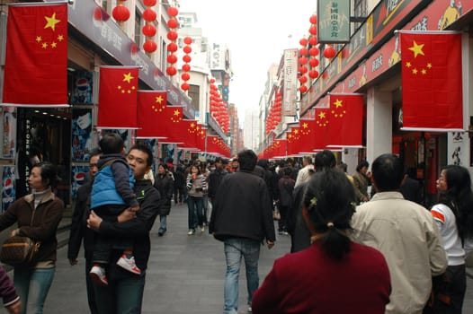 Crowd of people shopping during Chinese holiday in Shenzhen city, Guangdong province. Streets are decorated with national flags.