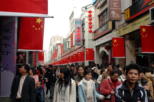 Crowd of people shopping during Chinese holiday in Shenzhen city, Guangdong province. Streets are decorated with national flags.