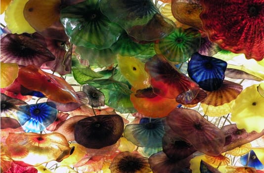 hand blown glass flowers, hanging from a ceiling.