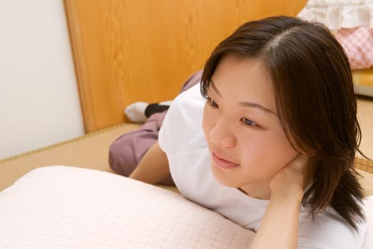 Leisure of Asian woman lie on ground of room in home.