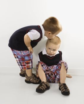 Caucasian twin boy kissing other twin boy on head.