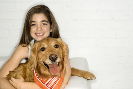 Female adolescent Caucasian holding Golden Retriever dog.