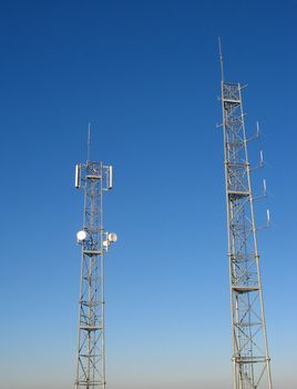 image of two pylons with antennas in a blue sky