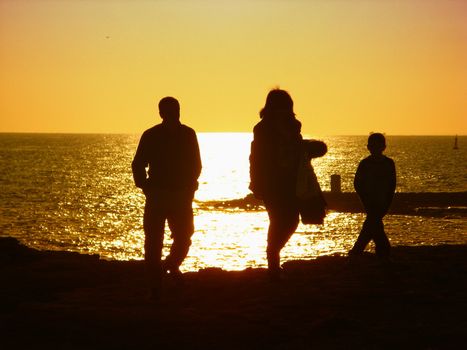 father, mother and son walking at sunset 
