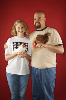 Caucasian mid-adult man and woman holding chickens.