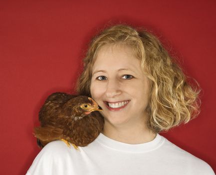 Caucasian mid-adult woman with chicken on shoulder.