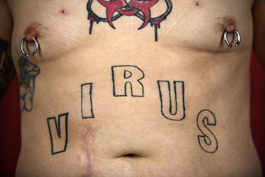 Caucasian mid-adult man midriff with tattoos and piercings.