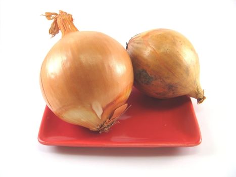 unpeeled onions on a red plate over a white background