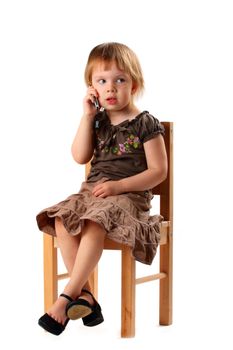 Little pretty girl in big shoes sitting on chair and talking by mobile phone with her friends.