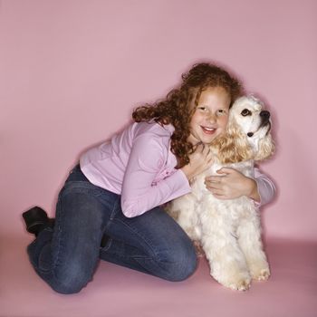 Caucasian female child hugging Cocker Spaniel dog.