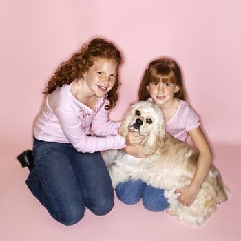 Caucasian female children holding Cocker Spaniel dog.