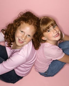 Caucasian female children sitting back to back.