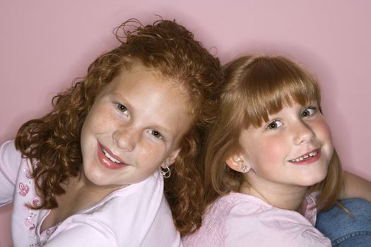 Caucasian female children sitting back to back.