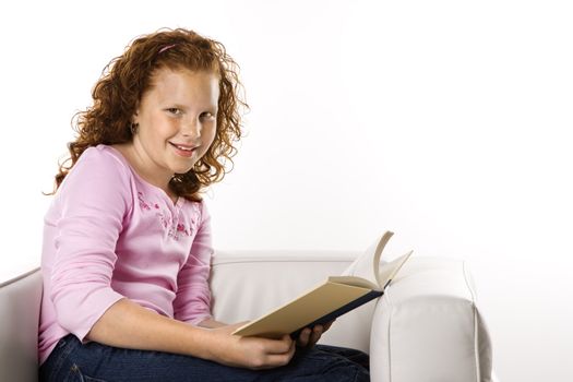 Caucasian female child sitting reading book.