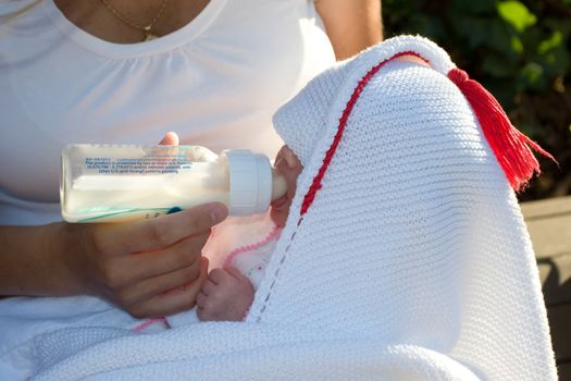 Mother feeding her child with bottle of breastmilk