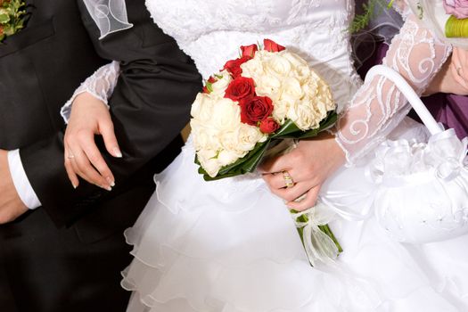 bouquet of red and white roses in the hands of newly married couple