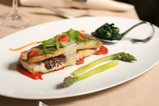 restaurant table with fish asparagus and spinach plate