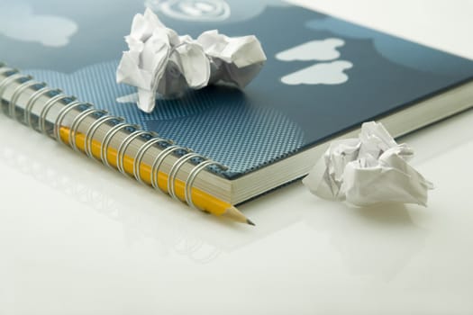 crumpled papers on notebook and yellow pencil