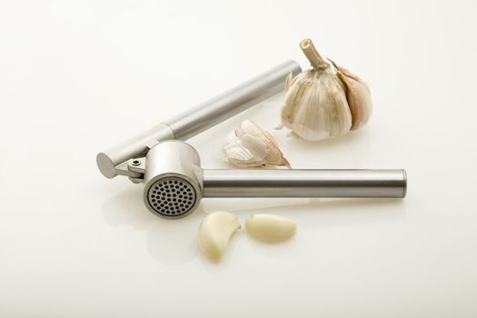 Garlic and a garlic press on a white background