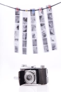 Old-time rusty photo-camera and film strips on white background 