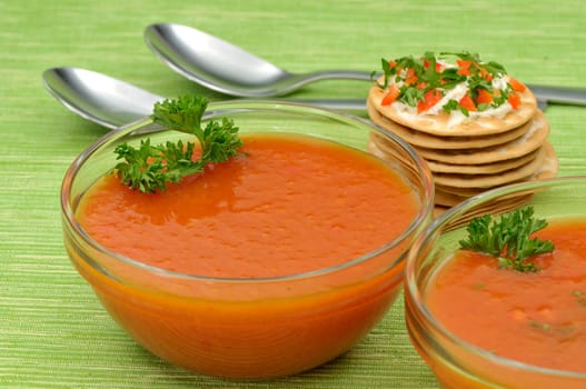 Bowls of tomato soup with parsley and a stack of cheese crackers