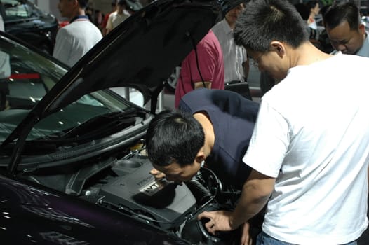 China, Shenzhen Moto - car show in exhibition center. Visitors watching European, American and Chinese cars. Crowd of people interested in newest moto technology.