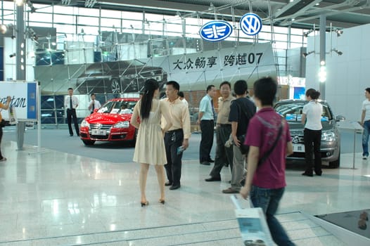 China, Shenzhen Moto - car show in exhibition center. Visitors watching European, American and Chinese cars. Crowd of people interested in newest moto technology.