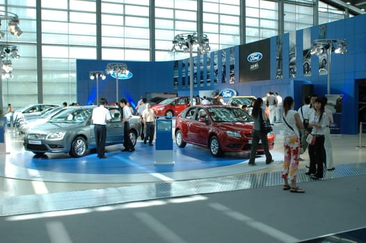 China, Shenzhen Moto - car show in exhibition center. Visitors watching European, American and Chinese cars. Crowd of people interested in newest moto technology.