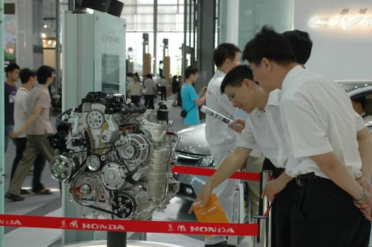 China, Shenzhen Moto - car show in exhibition center. Visitors watching European, American and Chinese cars. Crowd of people interested in newest moto technology.