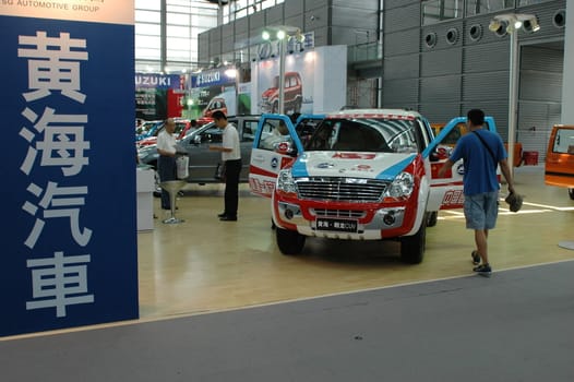 China, Shenzhen Moto - car show in exhibition center. Visitors watching European, American and Chinese cars. Crowd of people interested in newest moto technology.