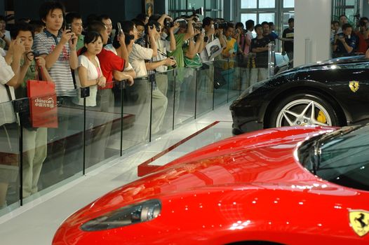 China, Shenzhen Moto - car show in exhibition center. Visitors watching European, American and Chinese cars. Crowd of people interested in newest moto technology.