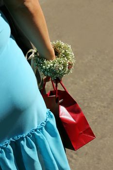 Woman with shopping bag walking down street, seen from behind.