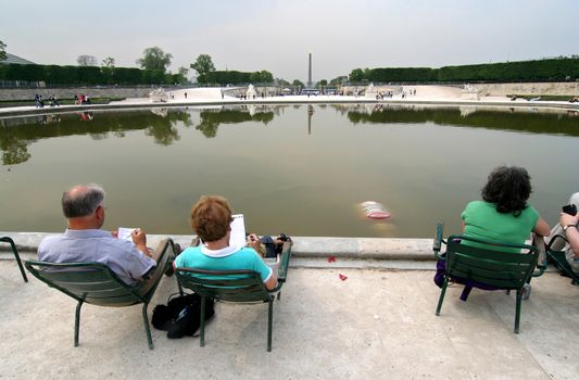 Paris. Couple doing crossword puzzles in the Jardin des Tuillieries.