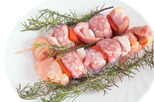 raw pork kebab on a plate with rosemary isolated on white background with clipping path
