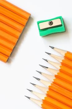 Sharpener and few yellow wooden pencils lying in a row on white background