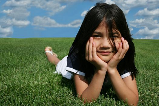 Little girl lying on grass in summer